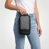 Vrouw in wit T-shirt en jeans houdt een zwarte packing cube met meshvak aan de voorkant.