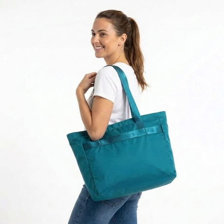 Vrouw draagt de Zeeksack Packable Travel Tote in Petrol Blue over haar schouder
