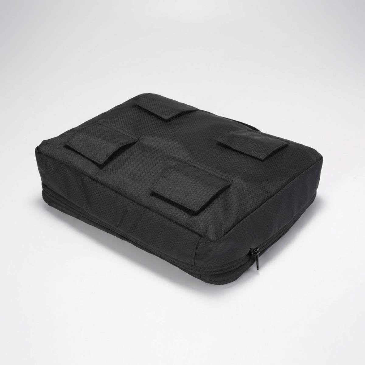 Zwarte packing cube van onderen gezien met vier klittenbandbevestigingen aan de onderkant.