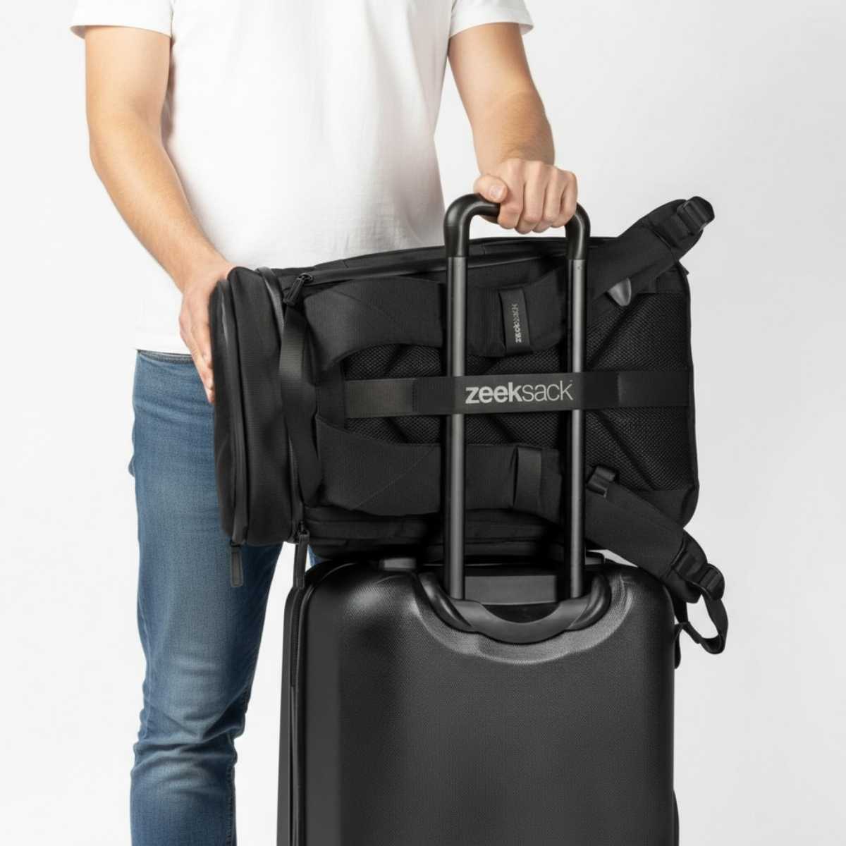 Een zwarte rugzak bevestigd aan de handgreep van een handbagagekoffer.