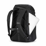 Zwarte rugzak met een zilverkleurige laptop gedeeltelijk in het zijvak geschoven.