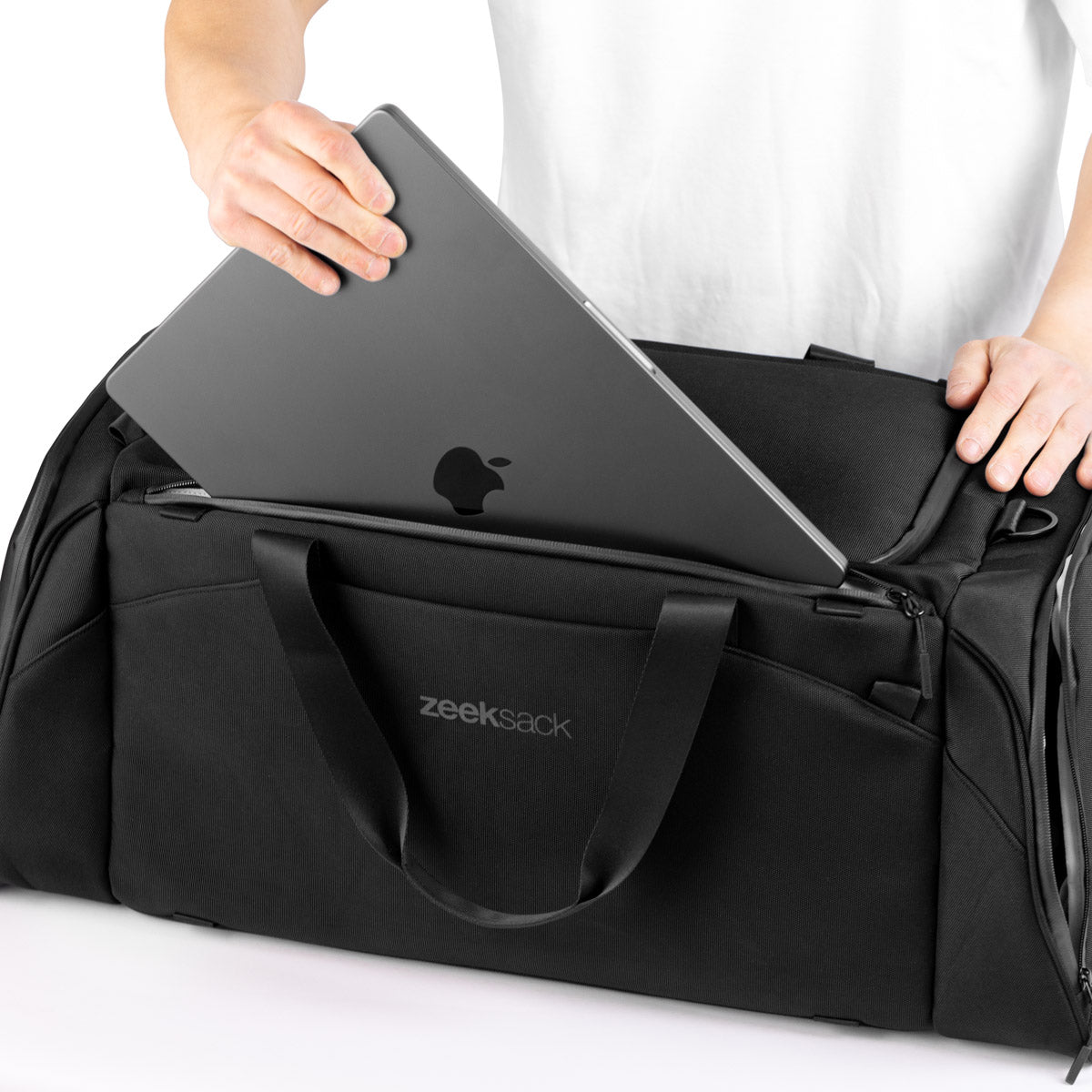 Man plaatst een laptop in het aparte laptopvak van de duffeltas.