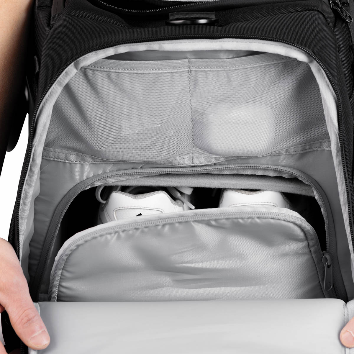 Schoenen in een apart schoenenvak van de tas, met kleinere accessoires in het vak erboven.
